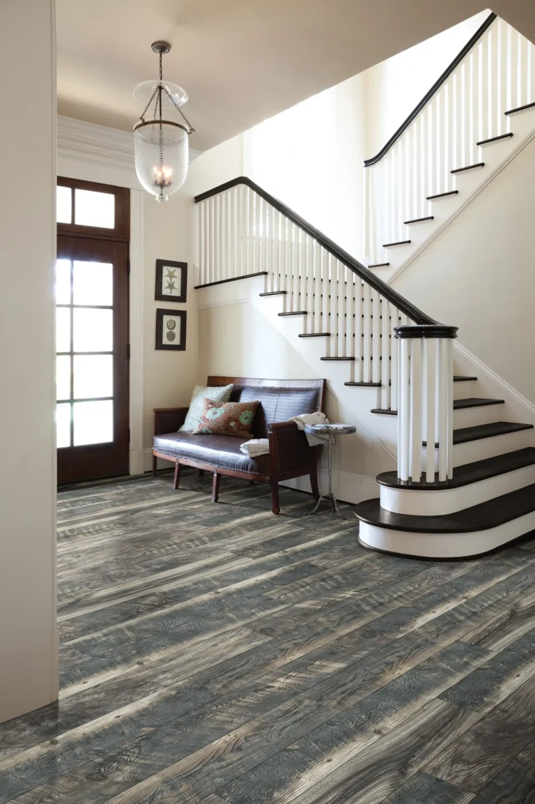 Neo Concept renovated Entryway with a wooden staircase, natural light coming through glass-paneled doors, and rustic wood flooring installation in blended gray and brown tones, featuring a wooden bench with patterned pillows.